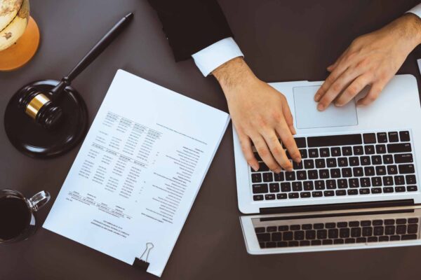 Top view lawyer or judge working on his desk with laptop at law firm or court, drafting legal documents with fairness and ethical judgment for lawsuits and litigation.