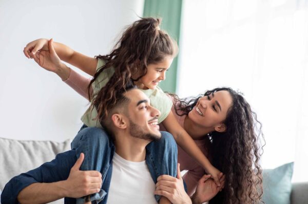 Mum, dad and daughter sitting on the sofa smiling