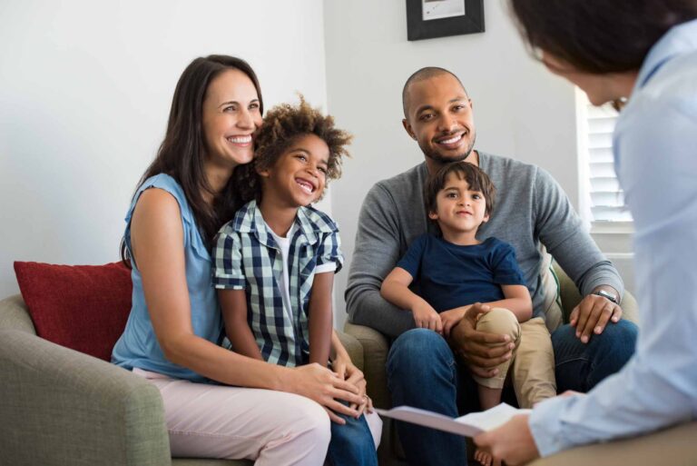 Happy young family sitting on couch talking to a woman