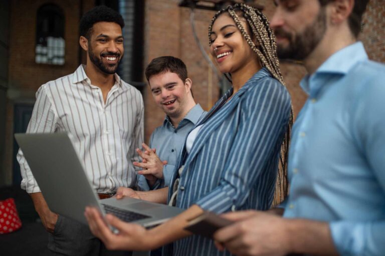 Cheerful young businesspeople with laptop working in office