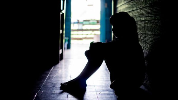 Sad girl crying while sitting on the floor in dark room