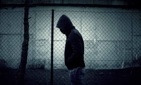 Young man in hoodie and mask walking in the park