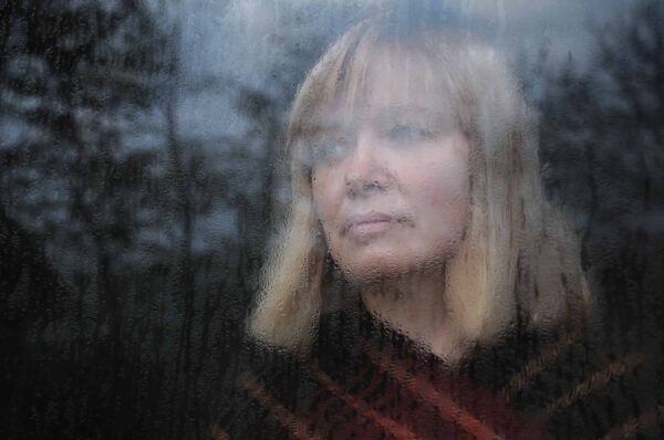 Portrait,Of,The,Middle-aged,Woman,Looking,Through,The,Window,On