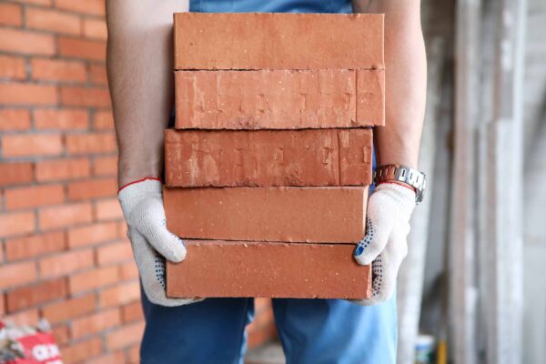 Gloved,Builder,Manually,Carries,Brick,Construction.,Building,Bricks,Are,Used