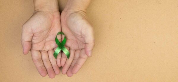 Hand,Hold,Green,Ribbon,On,White,Background.,Kidneys,Cancer,Awareness