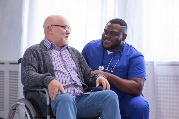 Caregiver talking to old man in a wheelchair