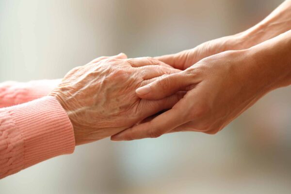 Old,And,Young,Holding,Hands,On,Light,Background,,Closeup