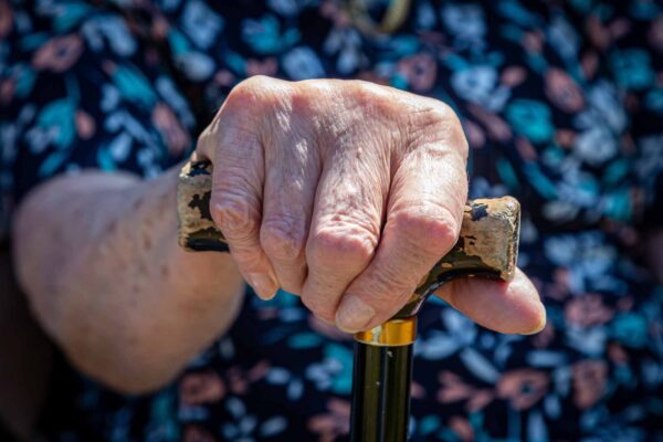 A close up of a woman's hand holding a walking stick