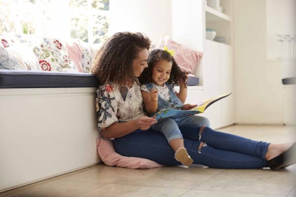 Mother,Sitting,On,The,Floor,Reading,A,Book,With,Her