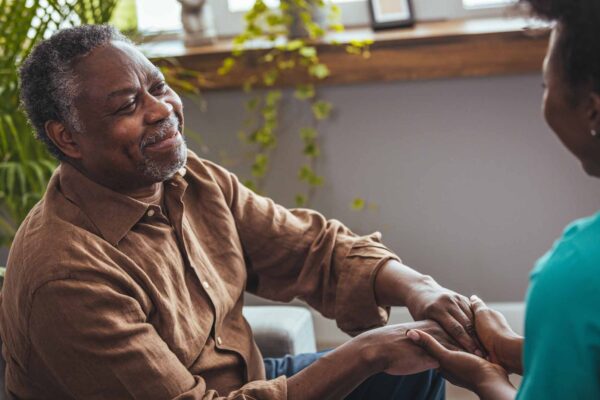 Female healthcare worker holding hands of senior man at care home