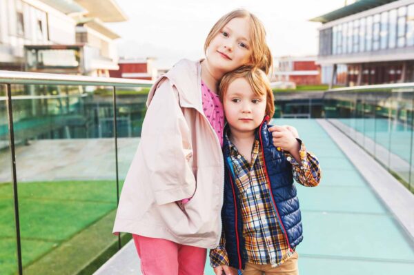 Little brother and big sister hugging outside