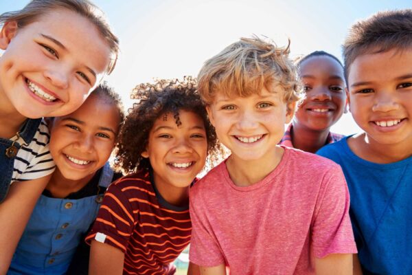 Close up of young kids in a park smiling to camera