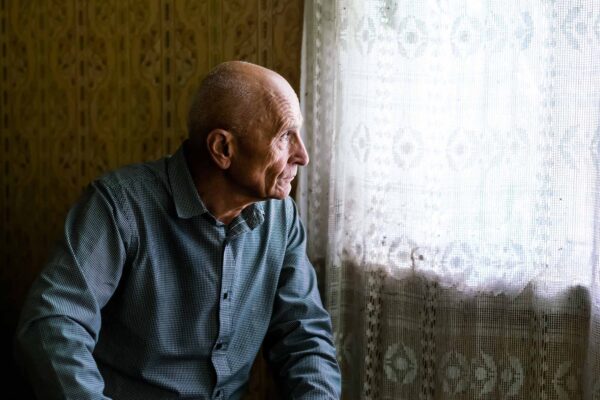 Older,Sad,Bald,Man,Siting,On,Sofa,In,Village,House