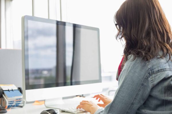 Rear,View,Of,Businesswoman,Using,Desktop,Computer,In,Creative,Office