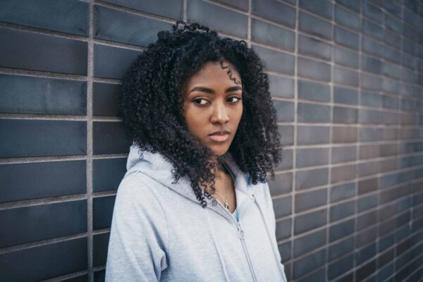 Young woman looking sad leaning against a wall