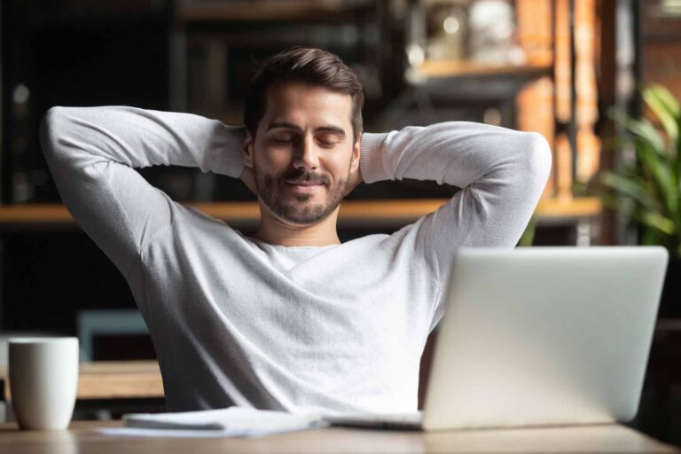 Relaxed man sitting at a desk with his laptop