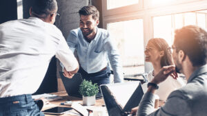 people shaking hands and smiling while working in an office