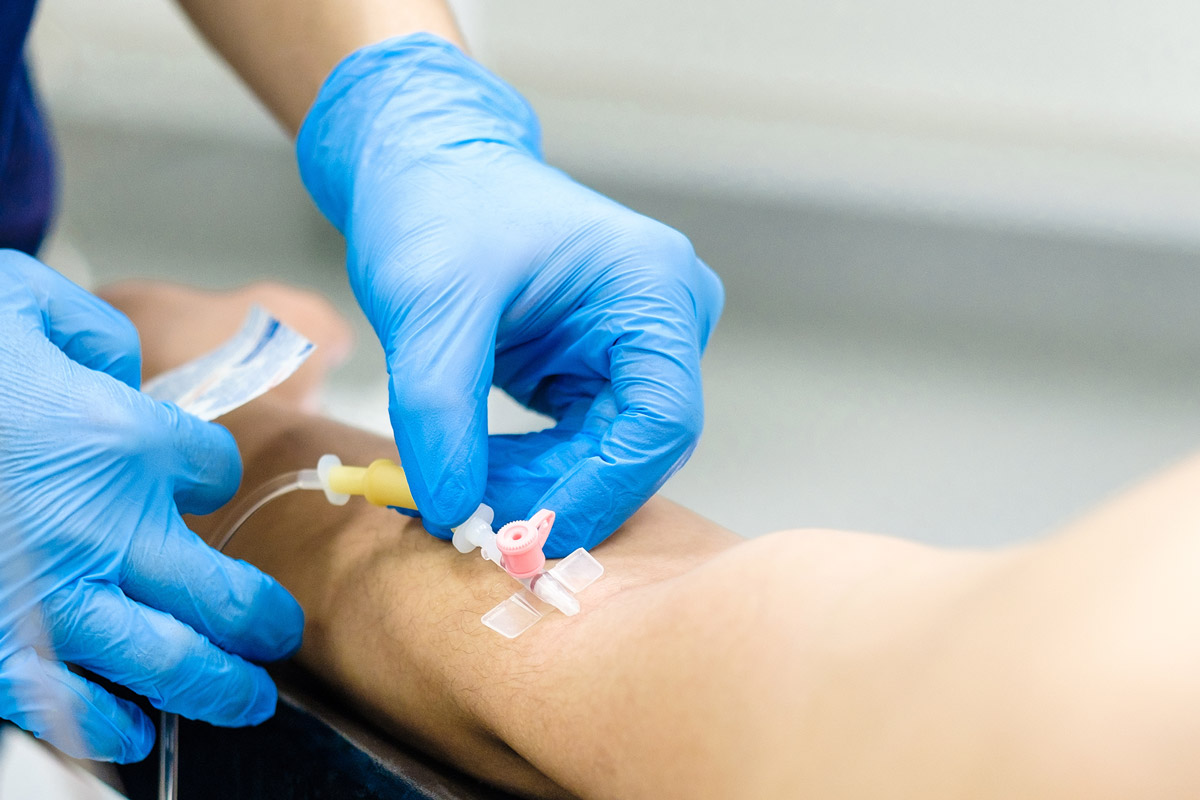 Inserting the dropper needle into the patient's arm.