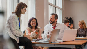 Co-workers talking though information on a laptop in a board room.