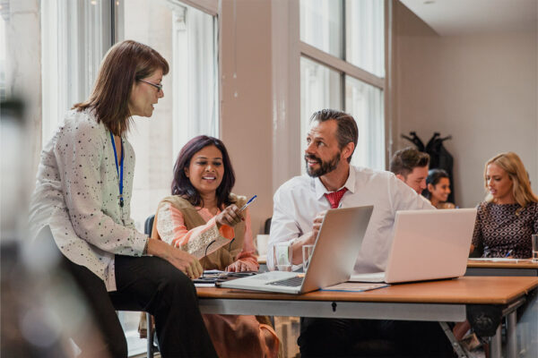 Co-workers talking though information on a laptop in a board room.