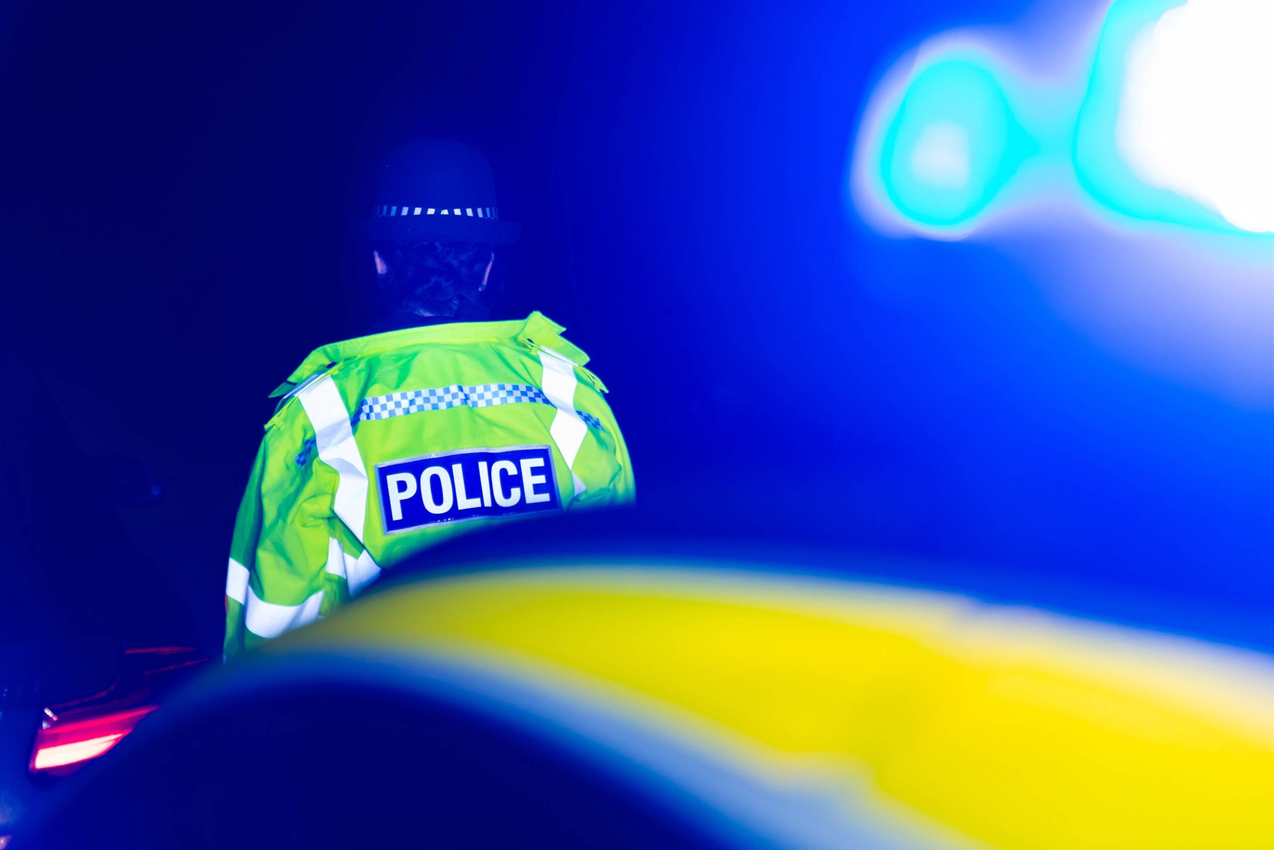 Police Officer at nighttime scene with Blue emergency lights